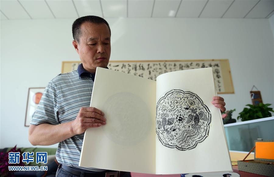 5月17日，文物修复技师张芯语在去除画卷上的附着物。
